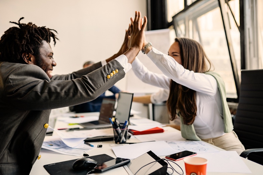 Colleagues celebrating with a high five at a desk